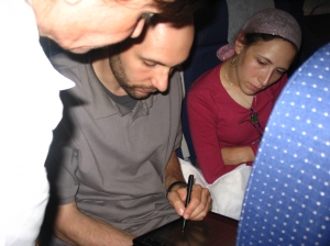 Woodmere's Eli and Chana Alony, now of Beit El, sign a tablet computer during the flight to officially complete their aliyah and become citizens of the State of Israel.